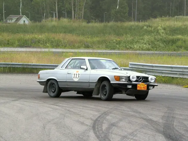 The image shows a white Mercedes-Benz 280SL on a race track, surrounded by a railing, grass,...