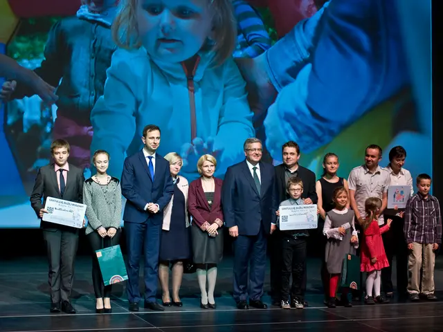 The image shows a group of people standing on top of a stage, with some of them holding bags and...