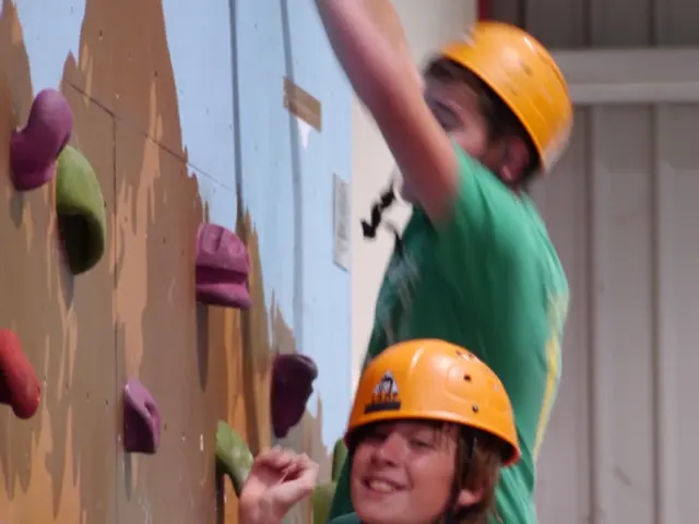 In this image I can see a person climbing the wall, beside them there is a fire extinguisher.