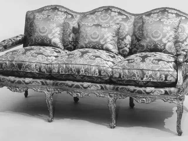 The image shows a black and white photo of a couch with pillows on it. The couch has a classic...