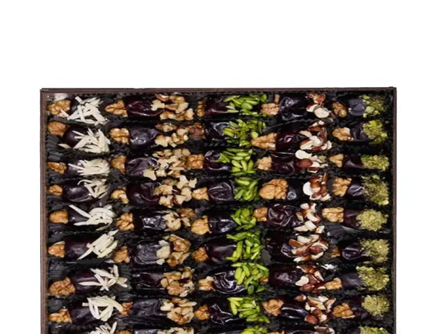 The image shows a box filled with a variety of dried fruits and nuts on top of a white background....