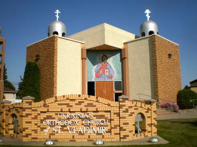 The image shows the Ukrainian Orthodox Church of St. Vladimir, with a wall with text on it, grass...