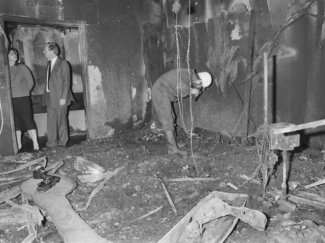 The image shows a group of three people standing in a room that has been destroyed by a fire. The...
