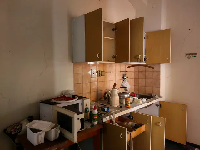 The image shows a small kitchen with a microwave oven sitting on top of a counter, surrounded by...