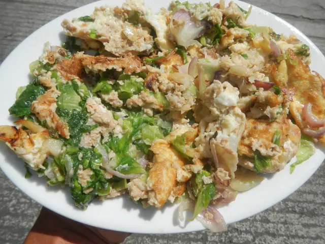 The image shows a person holding a white plate filled with a salad on top of a table. The plate is...