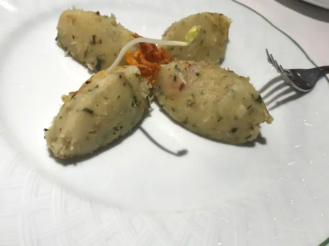 The image shows a white plate topped with three pieces of food, a fork, and a knife. The plate is...