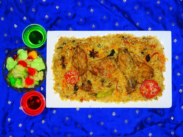 The image shows a white plate topped with a generous portion of Hyderabadi Chicken Biryani,...