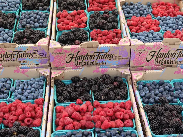 The image shows boxes of fresh berries on display at a farmers market. The boxes are filled with a...