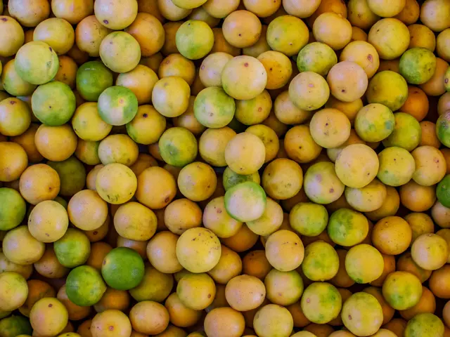 The image shows a box full of mangoes sitting on top of a table. The mangoes are a vibrant...