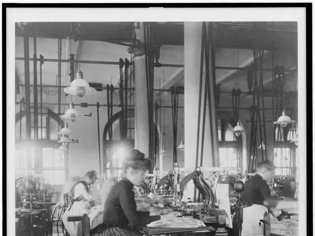 The image shows a black and white photo of women working in a factory. There are several people...