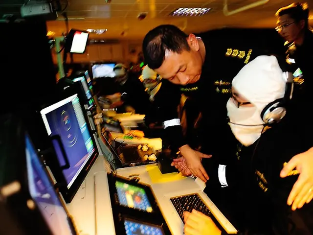 The image shows a group of people wearing headsets and working on computers in a control room....