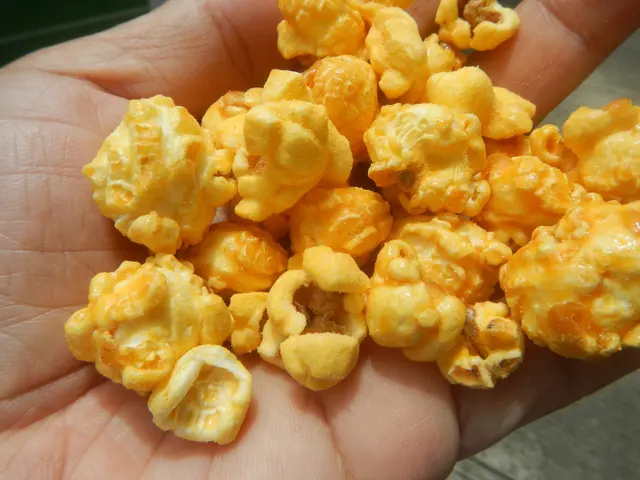 The image shows a person holding a handful of popcorn in their hand, with the floor visible at the...