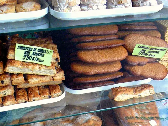The image shows a bakery with a display case filled with lots of different types of cookies, each...