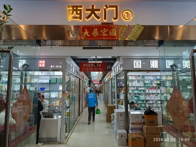 The image shows the inside of a Chinese pharmacy with people walking through it. There are glass...
