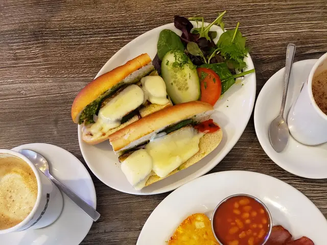 The image shows a wooden table topped with plates of food and cups of coffee, as well as saucers,...