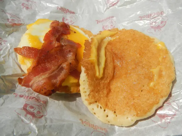 The image shows a bacon and egg breakfast sandwich on a piece of paper. The sandwich is composed of...