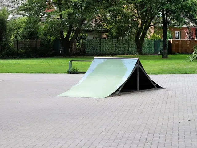 The image shows a park with a skateboard ramp in the middle of it, surrounded by benches, railings,...