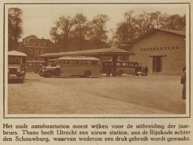The image shows an old photo of a bus station with several buses parked in front of it. There are...