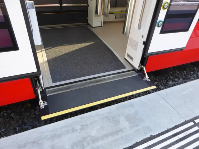 The image shows a red and white train with a black and white stripe running along the side of it....