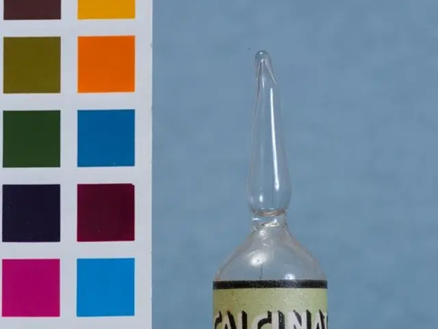 The image shows a small glass vial filled with white powder sitting next to a color chart with...