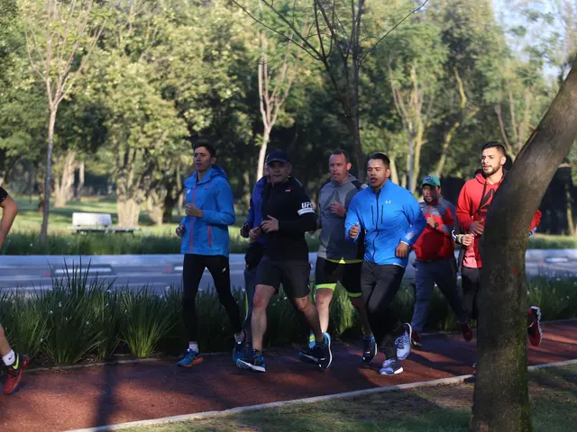 The image shows a group of people running in a park, surrounded by lush green grass, plants, and...
