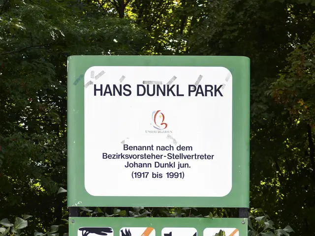 The image shows a Hans Dunkl Park sign in the middle of a forest, surrounded by trees. The sign is...