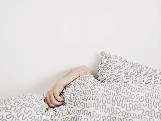 The image shows a person laying in bed with their hand on the pillow, surrounded by a white...