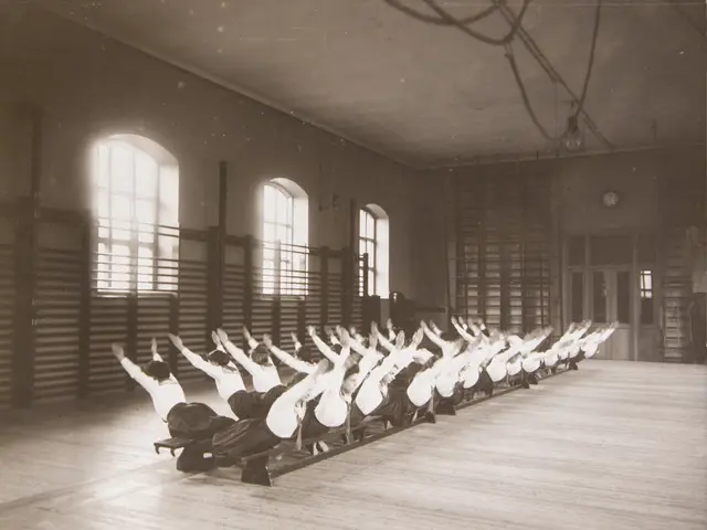The image shows a group of people doing pilates in a gym, with a wall in the background featuring...