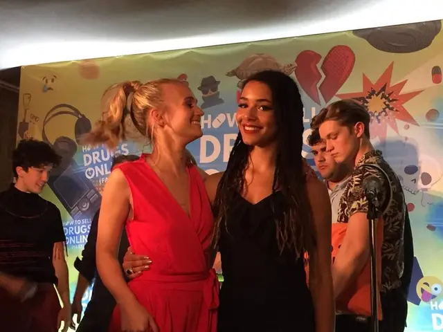 The image shows a group of people standing next to each other on a stage, with a banner in the...