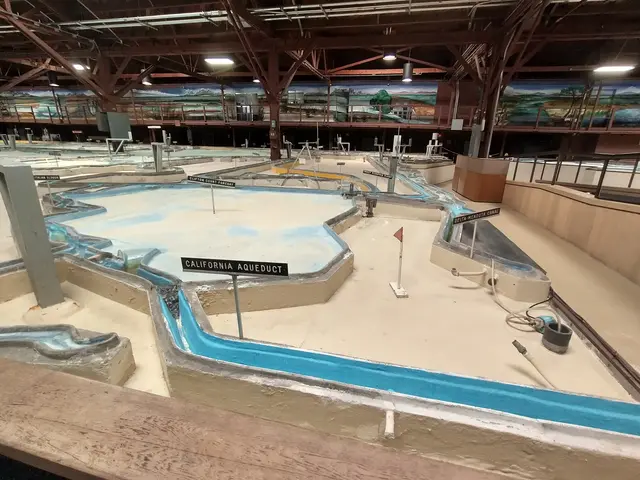 The image shows a large indoor water park with a lot of water slides, poles, boards with text,...