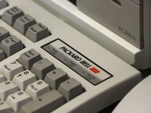 The image shows a close up of a white computer keyboard with a red button on it. The keypad is...