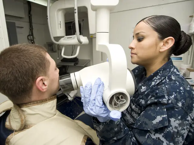 The image shows a man in a military uniform sitting in a chair while a woman in a blue uniform...
