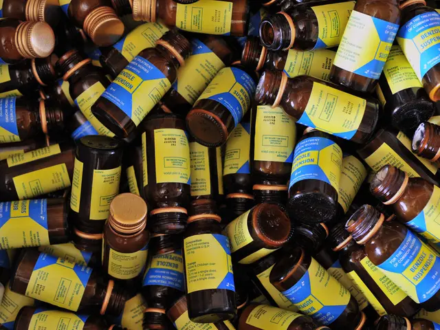 The image shows a pile of brown bottles with yellow labels sitting on top of each other. The...