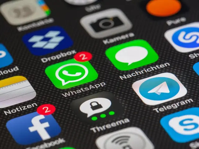 The image shows a close up of a cell phone with various apps on the screen, including Facebook,...